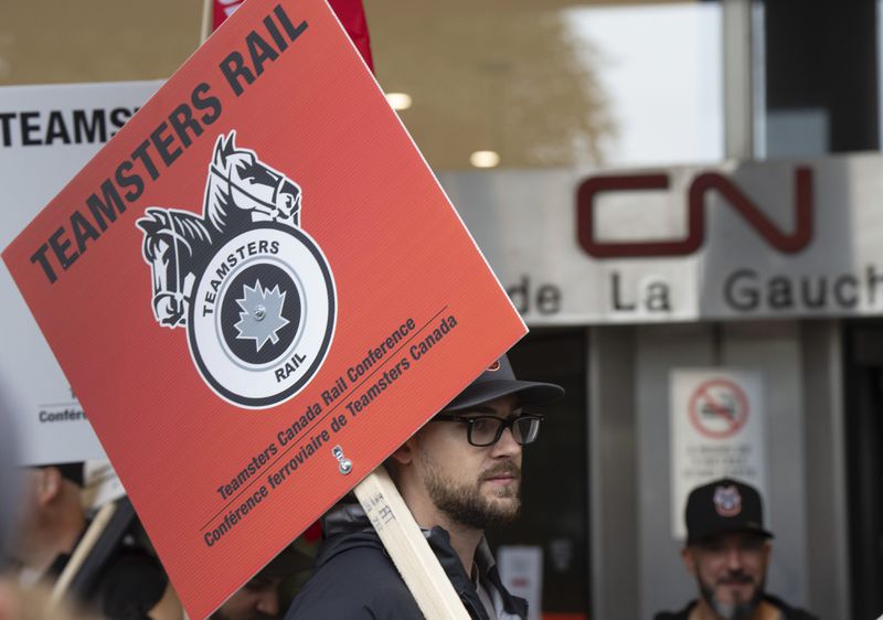 Rail workers picket in front of Canadian National headquarters on the first day of a nationwide rail shutdown, after workers were locked out by CN and CPKC when new contract agreements weren't reached by the midnight deadline, in Montreal, Thursday, Aug. 22, 2024. (Ryan Remiorz /The Canadian Press via AP)