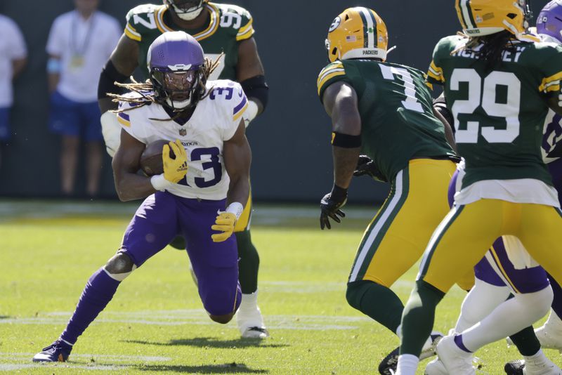 Minnesota Vikings running back Aaron Jones, left, runs the ball past Green Bay Packers linebacker Quay Walker (7) during the first half of an NFL football game Sunday, Sept. 29, 2024, in Green Bay, Wis. (AP Photo/Mike Roemer)