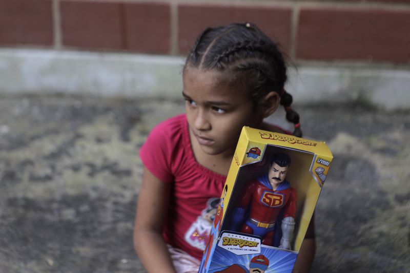 FILE - A child holds a "Super Bigote" action figure doll modeled after President Nicolas Maduro, a Christmas gifts delivered by government officials, in the Carayaca neighborhood of La Guaira, Venezuela, Dec. 27, 2022. (AP Photo/Jesus Vargas, File)