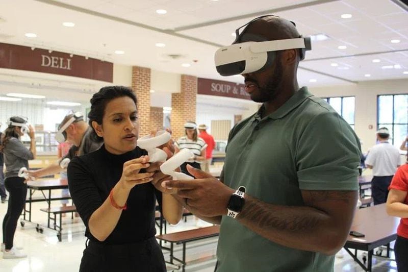 Prisms CEO Anurupa Ganguly, left, helps a Cobb teacher use his VR headset and controls during Monday’s training at Wheeler High School. (Photo Courtesy of Annie Mayne)