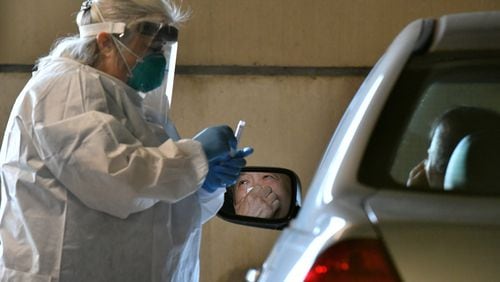 April 22, 2020 Duluth - A medical professional collects a nasal swab from a potential COVID-19 patient at a drive-through COVID-19 testing site for anyone who is experiencing symptoms at the Infinite Energy Center in Duluth on Wednesday, April 22, 2020. A drive-through COVID-19 testing center is open in Gwinnett County for anyone who is experiencing symptoms  - with no doctor's orders necessary. The Gwinnett, Newton and Rockdale County Health Department conducted 800 tests at the event venue, its second large-scale testing event in a week. (Hyosub Shin / Hyosub.Shin@ajc.com)