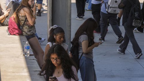 FILE - Students use their cellphones as they leave for the day the Ramon C. Cortines School of Visual and Performing Arts High School in downtown Los Angeles, Aug. 13, 2024. (AP Photo/Damian Dovarganes, File)