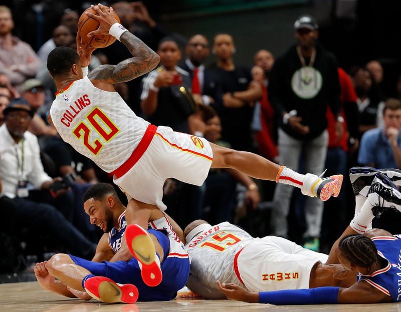 In a hard-edged game Monday at State Farm Arena, the Hawks John Collins  comes up with the ball over a sprawl of bodies that includes teammate Vince Carter and Philadelphia's Ben Simmons. 