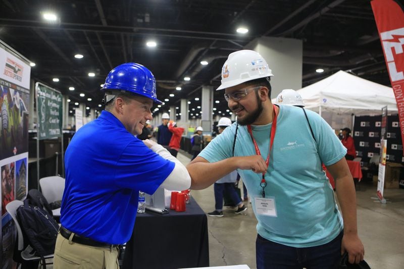 David Shea (left) and Adolfo Sosa touch elbows during the Construction Education Foundation of Georgia career expo on Thursday, March 12, 2020, at the Georgia World Congress Center in Atlanta. This year, because of the new coronavirus, additional safety measures were implemented. (Christina Matacotta for The Atlanta Journal-Constitution)