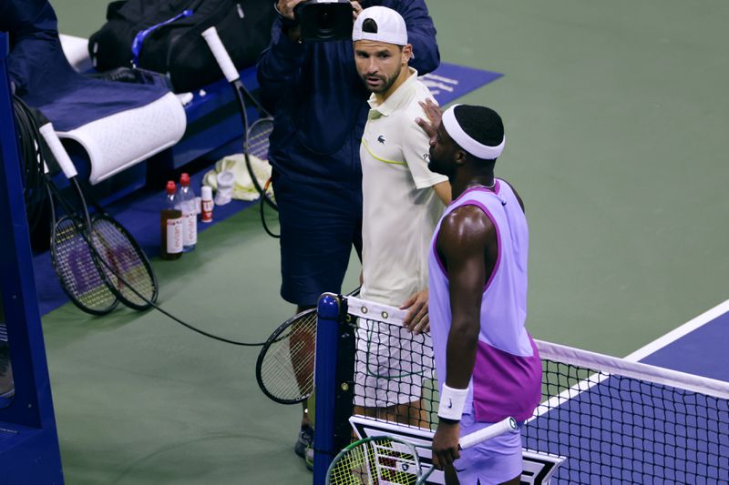 Grigor Dimitrov, of Bulgaria, left, gets a pat on the back from Frances Tiafoe, of the United States, after he was forced to retire due to an apparent injury during the quarterfinals of the U.S. Open tennis championships, Tuesday, Sept. 3, 2024, in New York. (AP Photo/Adam Hunger)