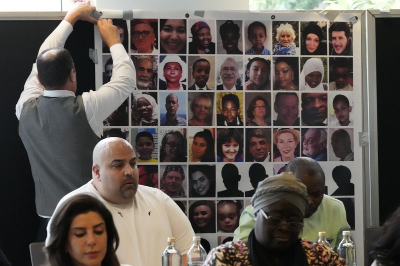 Relatives of the deceased and people directly affected by the Grenfell Tower fire, sit in front of a photo montage of the those who died, as they react to the final report into the fire being released in London, Wednesday, Sept. 4, 2024. The report on the Grenfell Tower fire in which 72 people were killed in June 2017, says decades of failure by government and industry made the high-rise a "death trap". (AP Photo/Frank Augstein)