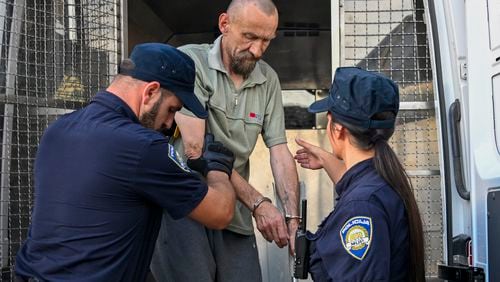 Detained suspect retired military police officer Kresimir Pahoki is assisted by police as he is transferred for interrogation in Bjelovar, central Croatia, Tuesday, July 23, 2024. The suspected gunman in a mass shooting at a nursing home in Croatia is facing 11 criminal charges, including murder, after he was accused of killing six people, including his own mother, and wounding as many more, police said on Tuesday. (Damir Krajac/Cropix via AP)