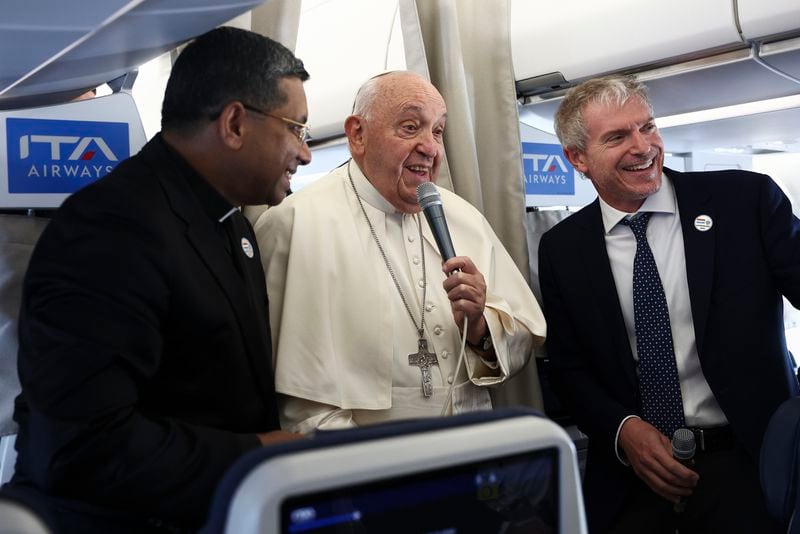 Pope Francis, center, speaks to the media aboard his flight bound for Luxembourg, where he will start a four-day apostolic journey in Luxembourg and Belgium, Thursday, Sept. 26, 2024. (Guglielmo Mangiapane/Pool Photo via AP)