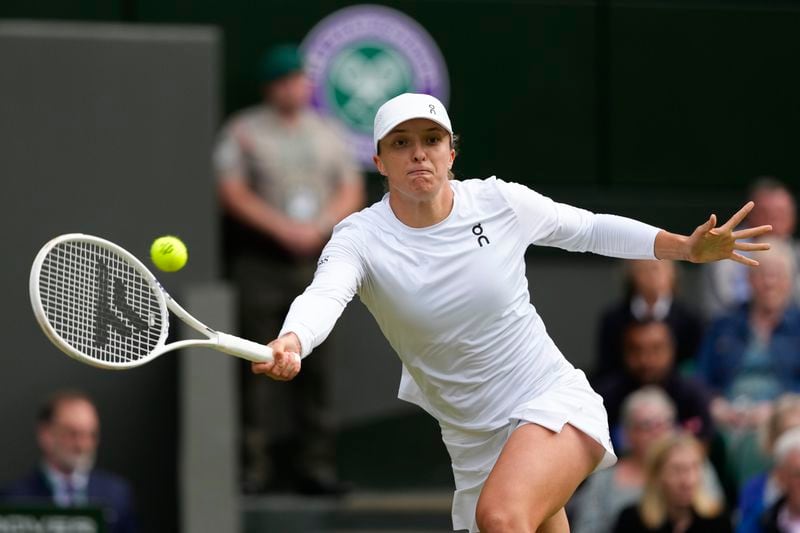 Iga Swiatek of Poland plays a forehand return to Petra Martic of Croatia during their second round match at the Wimbledon tennis championships in London, Thursday, July 4, 2024. (AP Photo/Kirsty Wigglesworth)