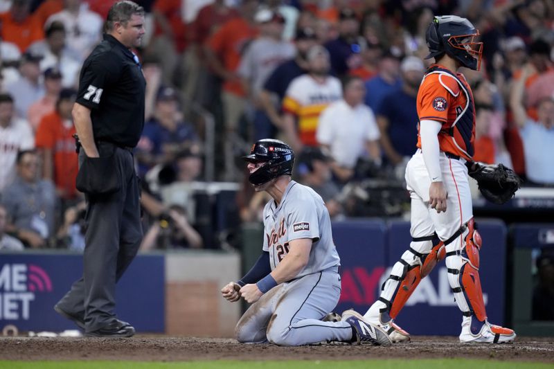 Detroit Tigers' Spencer Torkelson, center, celebrates in front of umpire Jordan Baker, left, and Houston Astros catcher Yainer Diaz, right, after Torkelson scored on a bases-clearing double by Andy Ibanez in the eighth inning of Game 2 of an AL Wild Card Series baseball game Wednesday, Oct. 2, 2024, in Houston. (AP Photo/Kevin M. Cox)