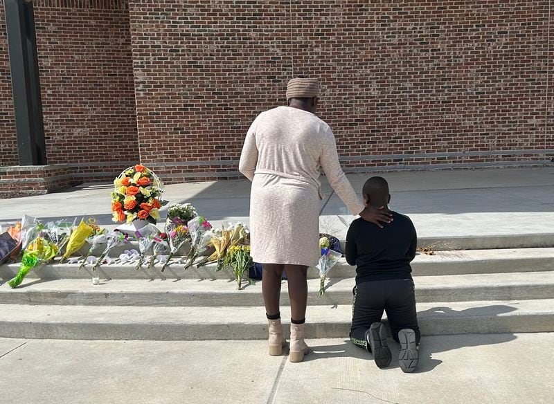 Cecil Oduory and her 10-year-old son Dylan Cheruiyot brought flowers to Jug Tavern Park to honor those killed in Wednesday's shooting.