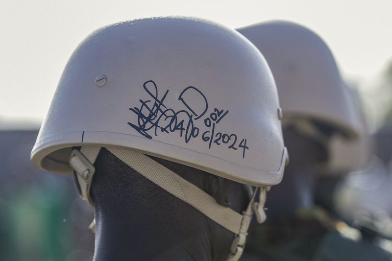A Kenyan police officer's helmet carries a signature and date of departure as his contingency stands at their base during a visit by Haitian Prime Minister Garry Conille in Port-au-Prince, Haiti, Wednesday, June 26, 2024. The first contingent of U.N.-backed foreign police arrived the previous day, nearly two years after the Caribbean country requested help to quell gang violence. (AP Photo/Marckinson Pierre)
