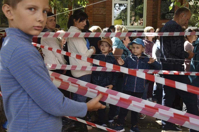 People evacuated from fighting between Russian and Ukrainian forces queue to receive humanitarian aid at a distribution center in Kursk, Russia, Monday, Aug. 12, 2024. (AP Photo)