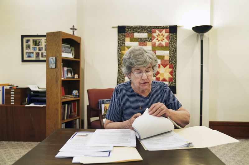 Sister Barbara McCracken looks through prior resolutions filed against various corporations, including Alphabet, Meta, Netflix and Chevron, at the Mount St. Scholastica Benedictine monastery in Atchison, Kan., Tuesday, July 16, 2024. McCracken currently serves in the monastery's business office helping with shareholder resolutions and investments. (AP Photo/Jessie Wardarski)