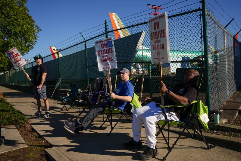 Boeing 737 Max aircrafts are seen behind fences as Boeing employees work the picket line while striking Tuesday, Sept. 24, 2024, next to the company's facilities in Renton, Wash. (AP Photo/Lindsey Wasson)