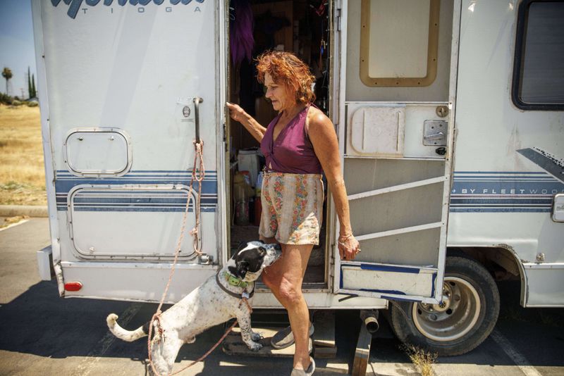 Evacuee Misti Morrow Mosley steps out of an RV to walk her dog at an evacuation shelter as the Thompson Fire burns, Wednesday, July 3, 2024, in Oroville, Calif. (AP Photo/Ethan Swope)