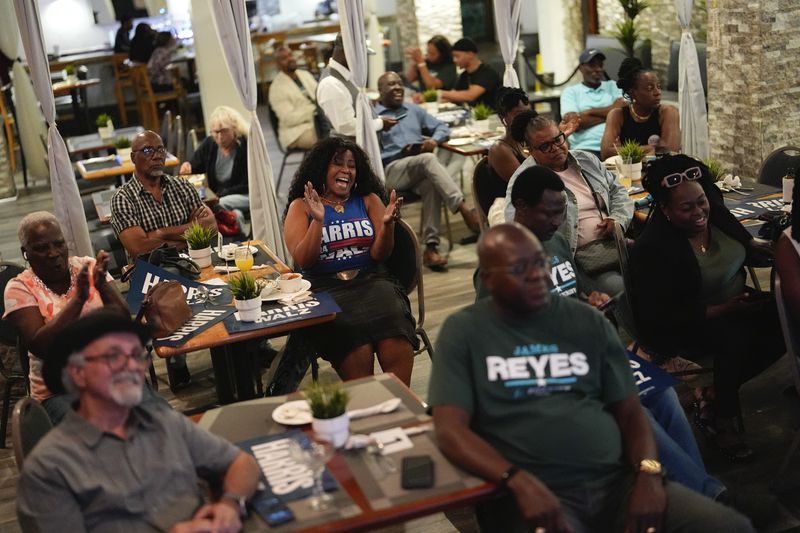 Teacher Elmire Desrouleaux, of North Miami, center, reacts during a presidential debate between Republican presidential nominee former President Donald Trump and Democratic presidential nominee Vice President Kamala Harris at a watch party organized by Democrats from Miami's Haitian-American community, Tuesday, Sept. 10, 2024, at Randy's Restaurant & Lounge in Miami. (AP Photo/Rebecca Blackwell)