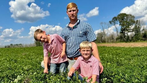 Peanut farmer Riley Davis sits in a peanut field along the Webster County border south of Plains with his sons, Drew (left), 4, and Luke, 7. (Joe Kovac Jr./AJC)