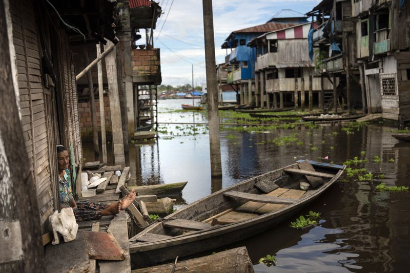 A woman sits in the doorway of her home in the Belen neighborhood of Iquitos, Peru, Saturday May 25, 2024. The Indigenous community in the heart of Peru's Amazon known as the "Venice of the Jungle" is hosting the Muyuna Floating Film Festival, celebrating tropical forests. (AP Photo/Rodrigo Abd)