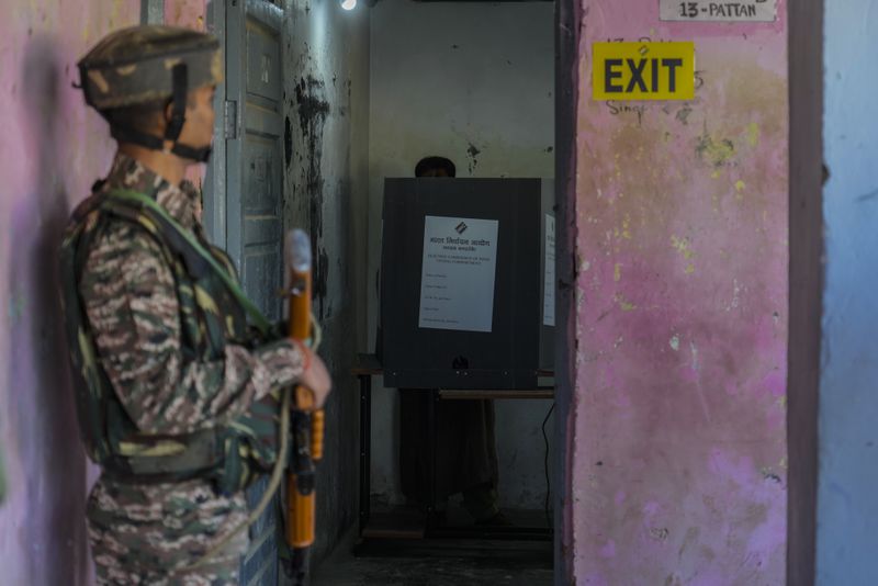 An Indian paramilitary soldier guards as a Kashmiri man casts his vote during the final phase of an election to choose a local government in Indian-controlled Kashmir, north of Srinagar, Tuesday, Oct.1, 2024. (AP Photo/Mukhtar Khan)