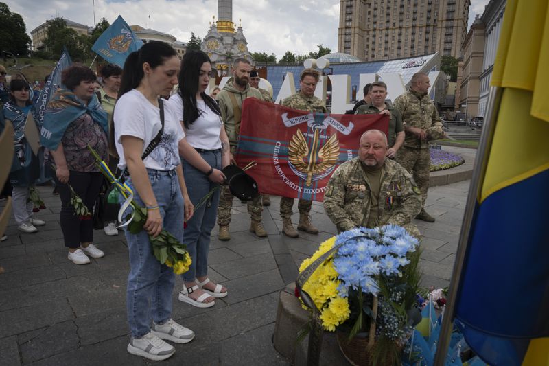 Veterans and people lay flowers to a spontaneous memorial to soldiers killed in war with Russia in the Independence square in Kyiv, Ukraine, Thursday, May 23, 2024. (AP Photo/Efrem Lukatsky)