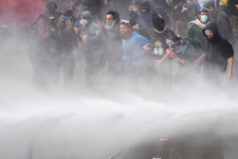 Anti-government protesters are sprayed by a police water cannon outside Congress, as lawmakers debate a reform bill promoted by Argentine President Javier Milei in Buenos Aires, Argentina, Wednesday, June 12, 2024. (AP Photo/Natacha Pisarenko)