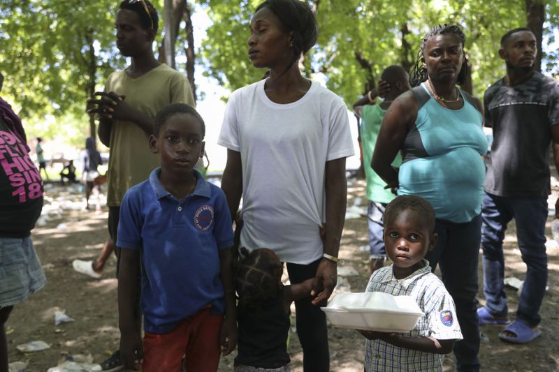 People displaced by armed attacks receive food from a nongovernmental organization in Saint-Marc, Haiti, Sunday, Oct. 6, 2024. (AP Photo/Odelyn Joseph)