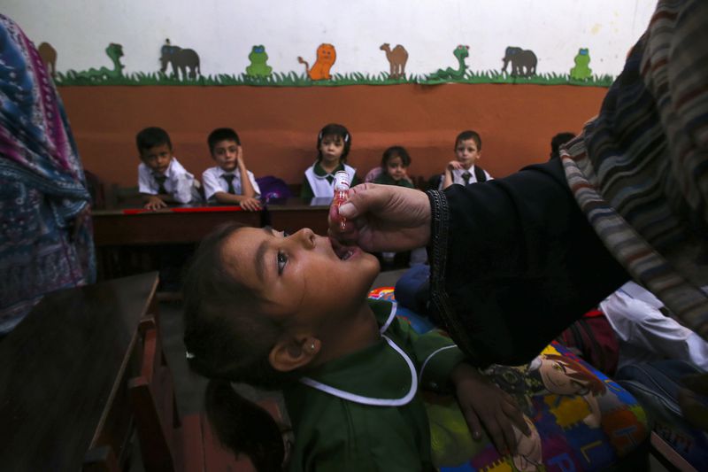 A health worker administers a polio vaccine to a child at a school in Peshawar, Pakistan, Monday, Sept. 9, 2024. (AP Photo/Muhammad Sajjad)