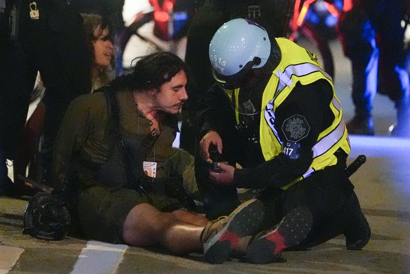 A person with a media ID is taken into custody by police police near the Israeli Consulate during the Democratic National Convention Tuesday, Aug. 20, 2024, in Chicago. (AP Photo/Julio Cortez)