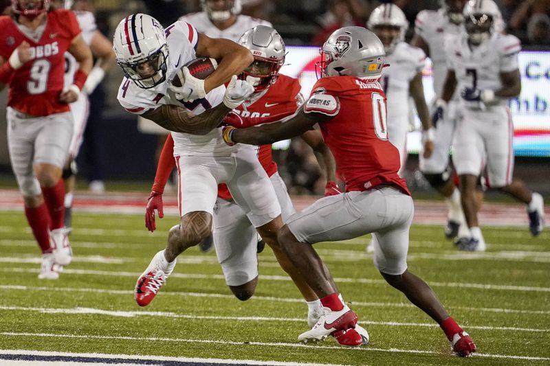 Arizona wide receiver Tetairoa McMillan (4) tries to break a tackle from New Mexico cornerback Bobby Arnold III (0) during the first half of an NCAA college football game Saturday, Aug. 31, 2024, in Tucson, Ariz. (AP Photo/Darryl Webb)