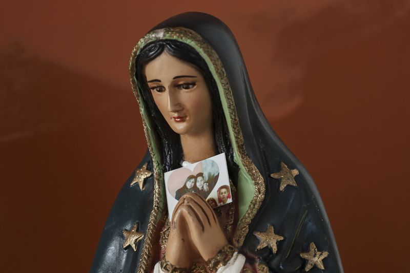 A statue of the Virgin of Guadalupe holds a photo of Veronica Rosas with her son Diego Maximiliano in Ecatepec, Mexico, Friday, Aug. 2, 2024. Diego went missing when he was 16 years old on Sept. 4, 2015. (AP Photo/Ginnette Riquelme)