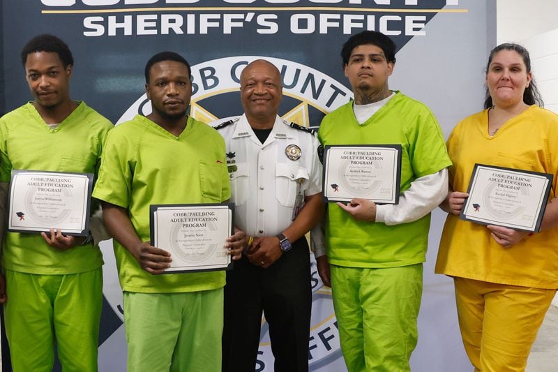 Inmates at Cobb County Detention Facility in Marietta pose for photos with Sheriff Craig Owens after receiving their GEDs on Tuesday, May 28, 2024. (Natrice Miller/ AJC)