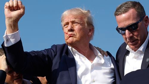 Former President Donald Trump pumps his fist July 13 as he is rushed offstage by Secret Service agents after being grazed by a bullet at a campaign rally in Butler, Pa. (Anna Moneymaker/Getty Images/TNS)