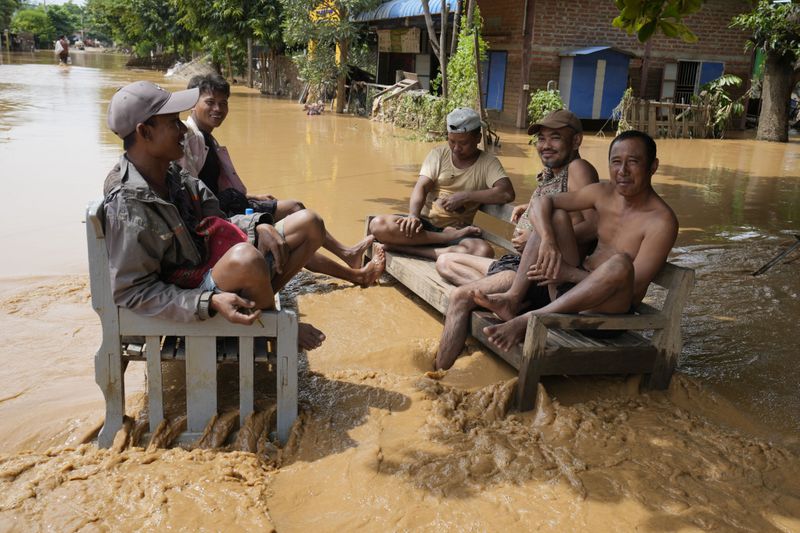 Local residents sit on a bench on a flooded road in Naypyitaw, Myanmar, Saturday, Sept. 14, 2024. (AP Photo/Aung Shine Oo)