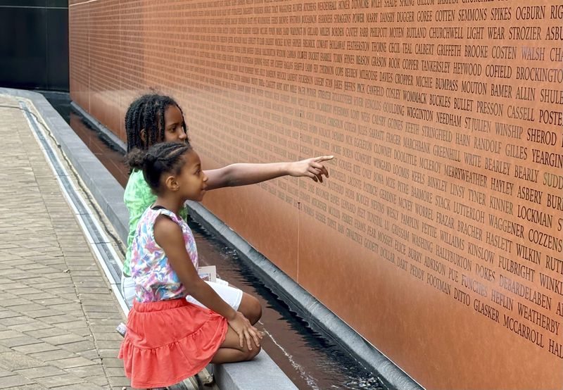 Gabriella Jackson, 7, and Erica Jackson,9, look for familiar names at the dedication of the National Monument to Freedom on Wednesday, June 19, 2024 in Montgomery, Ala. The monument is inscribed with 122,000 surnames that formerly enslaved people chose for themselves, as documented in the 1870 Census, after being emancipated at the Civil War's end. (AP Photo/Kim Chandler)