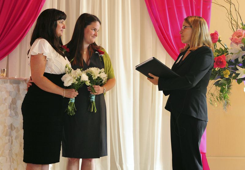 FILE - Julia Fraser, left, and Jessica Rohrbacher get married by Celebrant Holly Pruett, right, at the Melody Ballroom in Portland, Ore., May 19, 2014. (AP Photo/Steve Dykes, File)