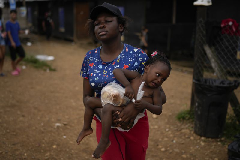 Dorcas Many, from Democratic Republic of the Congo, carries her daughter Maria Many at a camp where migrants who walked across the Darien Gap stop in Lajas Blancas, Panama, Thursday, Sept. 26, 2024. (AP Photo/Matias Delacroix)