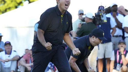 International team member Si Woo Kim, left, and celebrates with partner Byeong Hun An, after sinking the winning putt on the 18th hole during a second round foursome match at the Presidents Cup golf tournament at Royal Montreal Golf Club Friday, Sep.27, 2024 in Montreal. (Frank Gunn/The Canadian Press via AP)