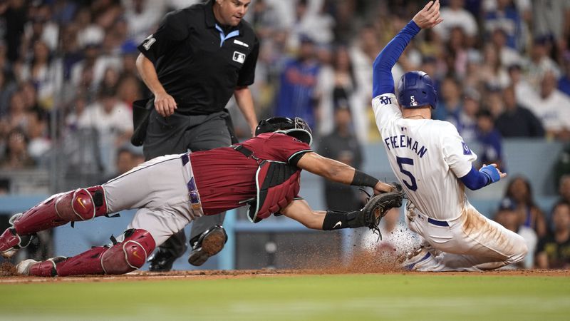 Los Angeles Dodgers' Freddie Freeman, right, is tagged out by Arizona Diamondbacks catcher Gabriel Moreno as he tried to score from third on the line out by Miguel Rojas during the third inning of a baseball game Wednesday, July 3, 2024, in Los Angeles. (AP Photo/Mark J. Terrill)