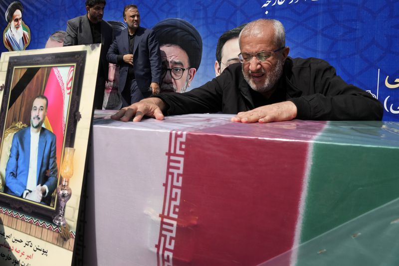A man mourns over the flag-draped coffin of Iranian Foreign Minister Hossein Amirabdollahian, who was killed in a helicopter crash along with President Ebrahim Raisi on Sunday in a mountainous region of the country's northwest, during a funeral ceremony at the foreign ministry in Tehran, Iran, Thursday, May 23, 2024. The death of Raisi, Foreign Minister Hossein Amirabdollahian and six others in the crash on Sunday comes at a politically sensitive moment for Iran, both at home and abroad.(AP Photo/Vahid Salemi)