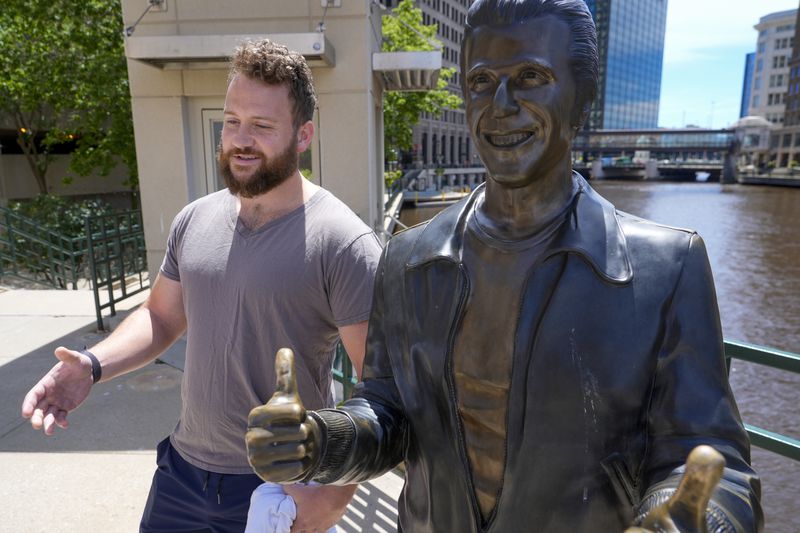 Jake Schneider talks about the Republican National Convention coming to Milwaukee next to the bronze Fonz statue Monday, July 1, 2024, in Milwaukee. (AP Photo/Morry Gash)