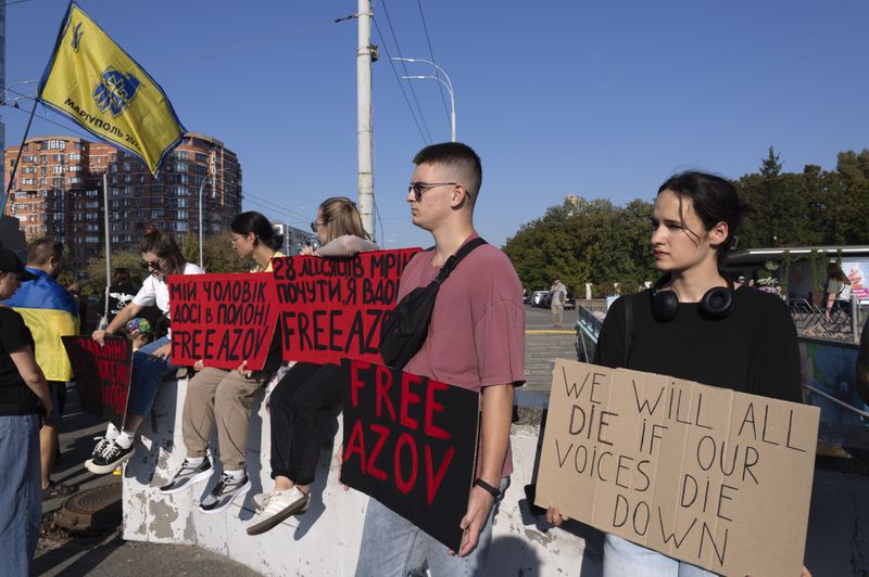 People hold signs as they participate in the weekly protest in Kyiv, Ukraine, Sunday Sept. 22, 2024 concerning the plight of Ukrainian Azovstal defenders still being held prisoner by the Russians. (AP Photo/Tony Hicks)