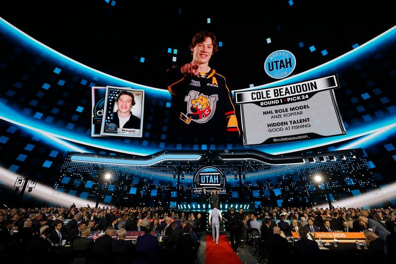 Cole Beaudoin, center bottom, heads to the podium after being selected by the Utah Hockey Club during the first round of the NHL hockey draft Friday, June 28, 2024, in Las Vegas. (AP Photo/Steve Marcus)