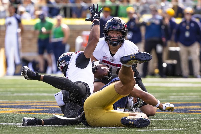 Northern Illinois line backer Christian Fuhrman, top, comes up with an interception after Northern Illinois safety Nate Valcarcel, left, deflected a pass intended for Notre Dame wide receiver Jaden Greathouse, right, during an NCAA college football game Saturday, Sept. 7, 2024, in South Bend, Ind. (AP Photo/Michael Caterina)