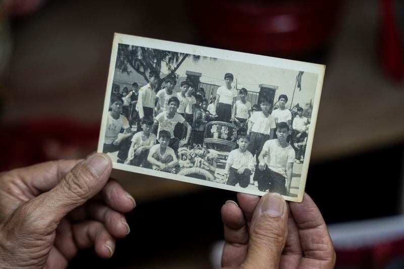 Villager Lo Yuet-ping holds up an old black and white photo where he can be seen in the second from top right at the Cha Kwo Ling village in east Kowloon, Hong Kong, Sunday, Aug. 25, 2024. (AP Photo/Chan Long Hei)