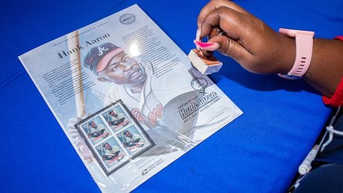 A United States Postal Service employee stamps Hank Aaron postage at the USPS Hank Aaron Commemorative Forever Stamp First Day of Issue Dedication Ceremony at Truist Park in Atlanta on Wednesday, July 31, 2024.  (Ziyu Julian Zhu / AJC)