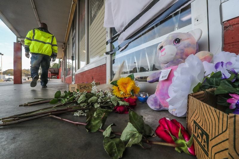 Flowers, cards and a stuffed animal are left outside the door of Beauty World in East Point after the owner, Hyun Chan Cha, was killed in an apparent robbery Tuesday.
