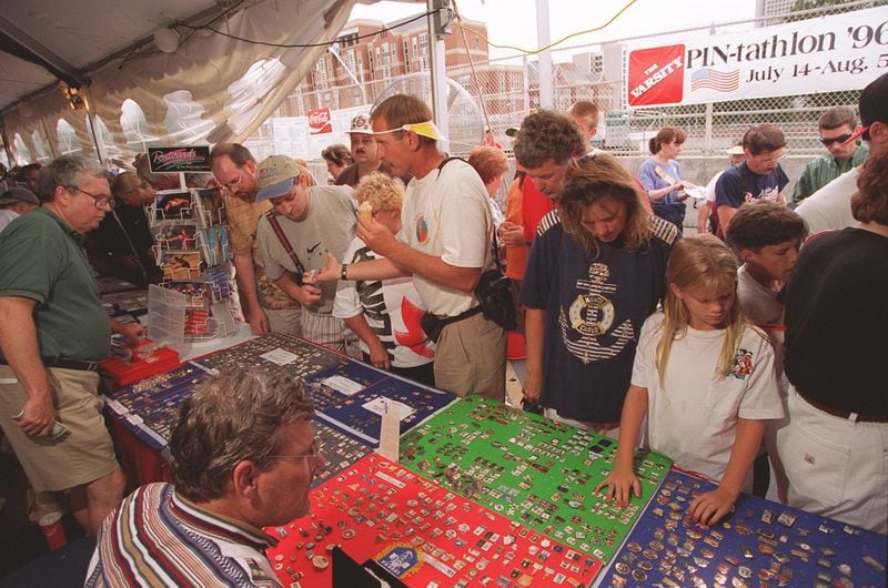 Pin traders look over goods in a tent at the downtown Atlanta location of the Varsity restaurant at Spring Street and North Avenue on Sunday July 28, 1996 during the 1996 Summer Olympic Games in Atlanta, Georgia. (AJC Staff Photo/Rich Mahan) 