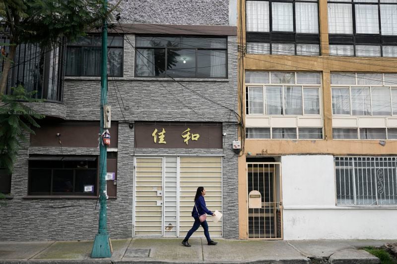 A woman walks in front of a house with Chinese letters in Viaducto Piedad in Mexico City, Wednesday, July 24, 2024. (AP Photo/Eduardo Verdugo)