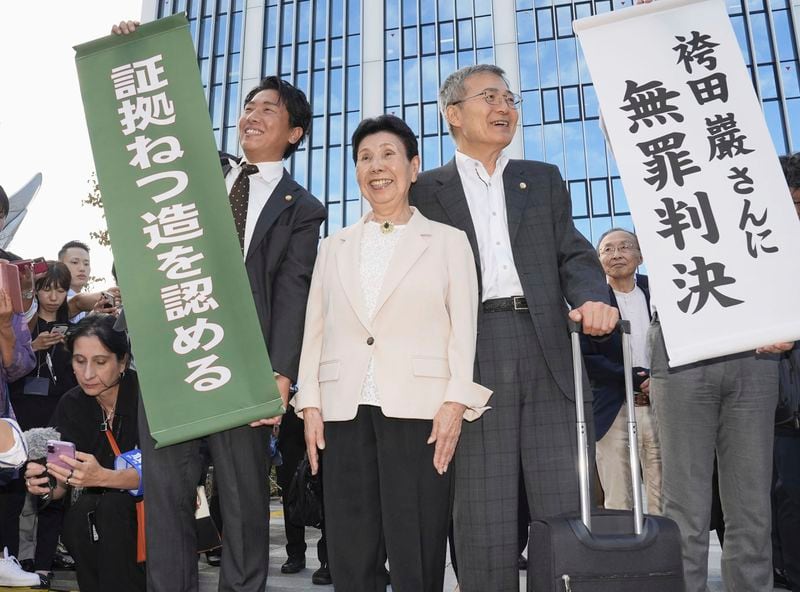 Hideko Hakamada, center, sister of 88-year-old former boxer Iwao Hakamada who has been on death row for nearly six decades after his murder conviction that his lawyers said was based on forced confession and fabricated evidence, reacts after a court ruled that her brother was not guilty in a retrial for a 1966 quadruple murder, in front of the court in Hamamatsu, Shizuoka prefecture, Thursday, Sept. 26, 2024. The signs read "Acquittal to Mr. Iwao Hakamada, " right, and "Acknowledged fabrications of evidence." (Kyodo News via AP)